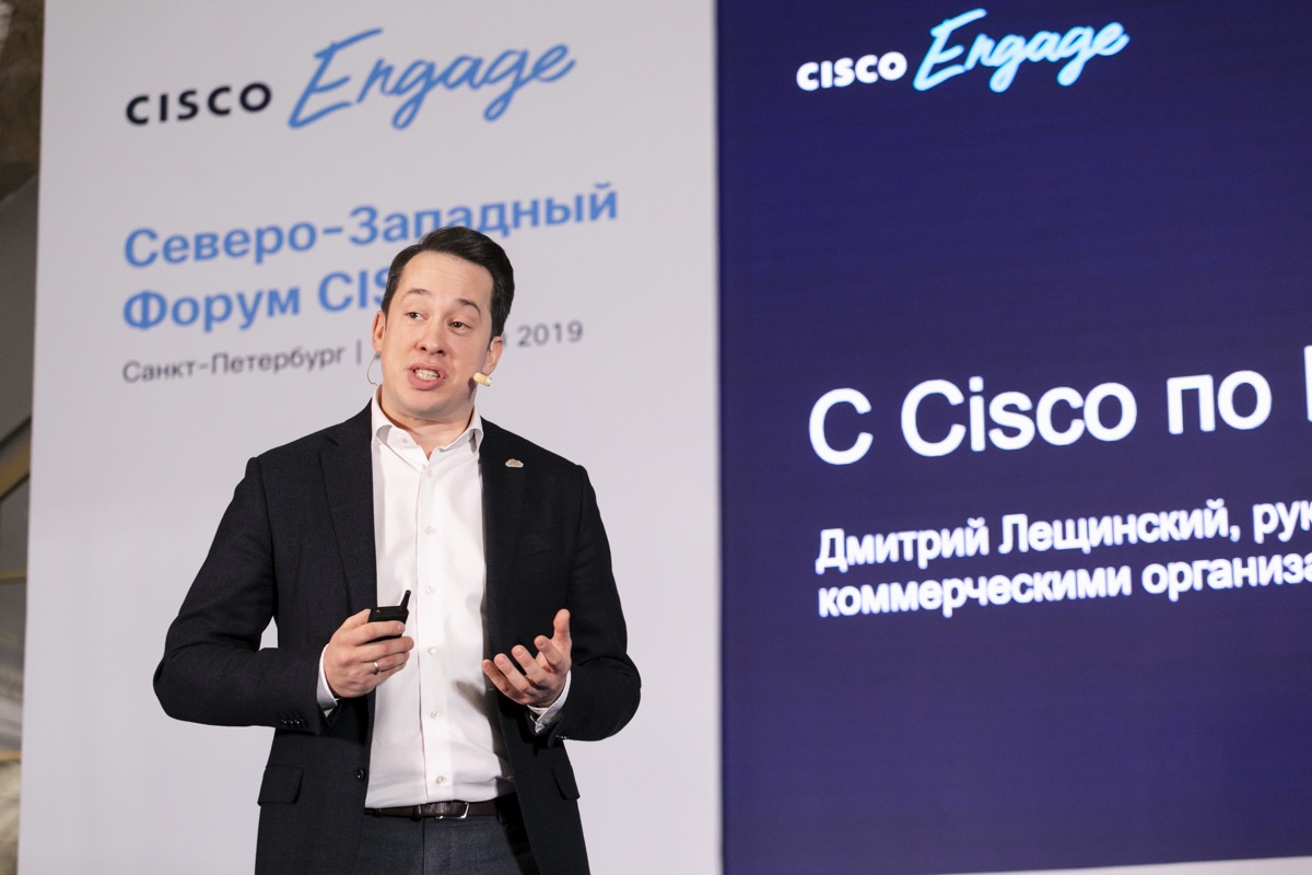 Man speaks on stage in front of a large Cisco Engage screen.
